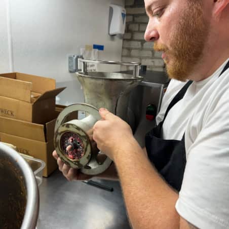A man working a commercial meat grinder